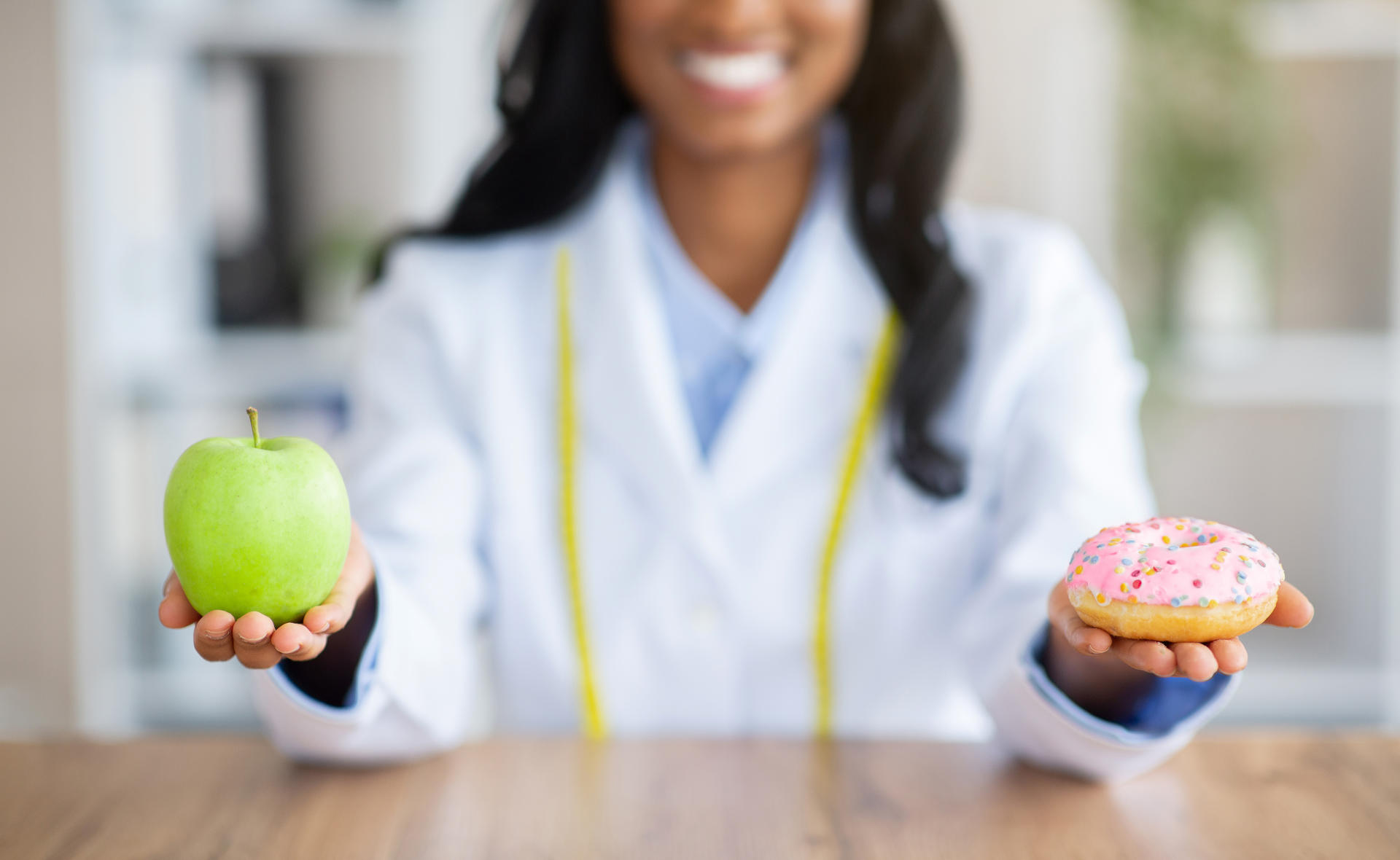 Dietista comparando una manzana y un dónut