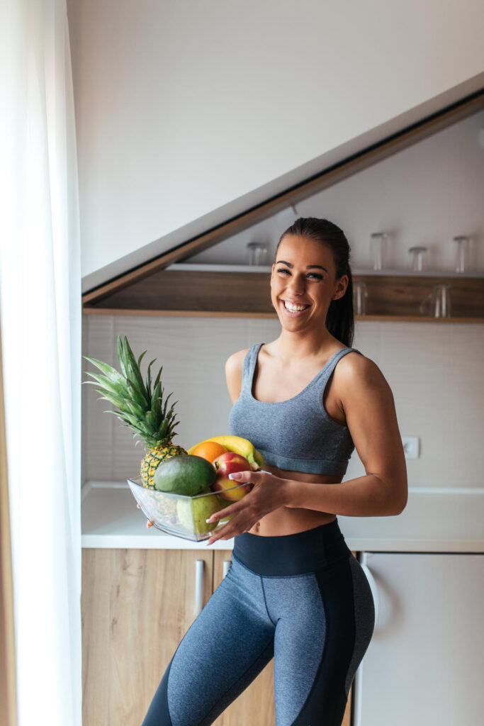 Mujer en ropa deportiva con fruta: mejorar la composición corporal sin obsesionarse con el peso
